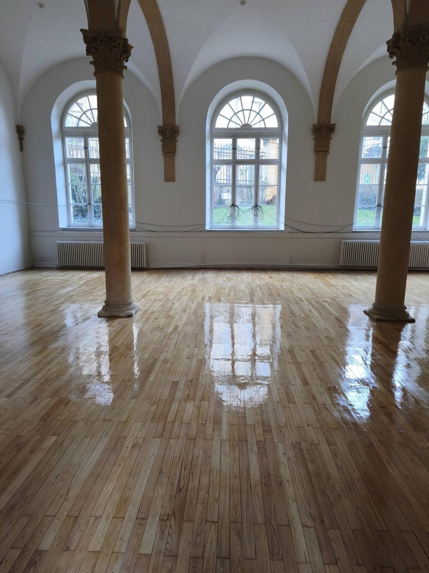 Grande salle voûtée à colonnes, fenêtres cintrées et parquet remis à neuf