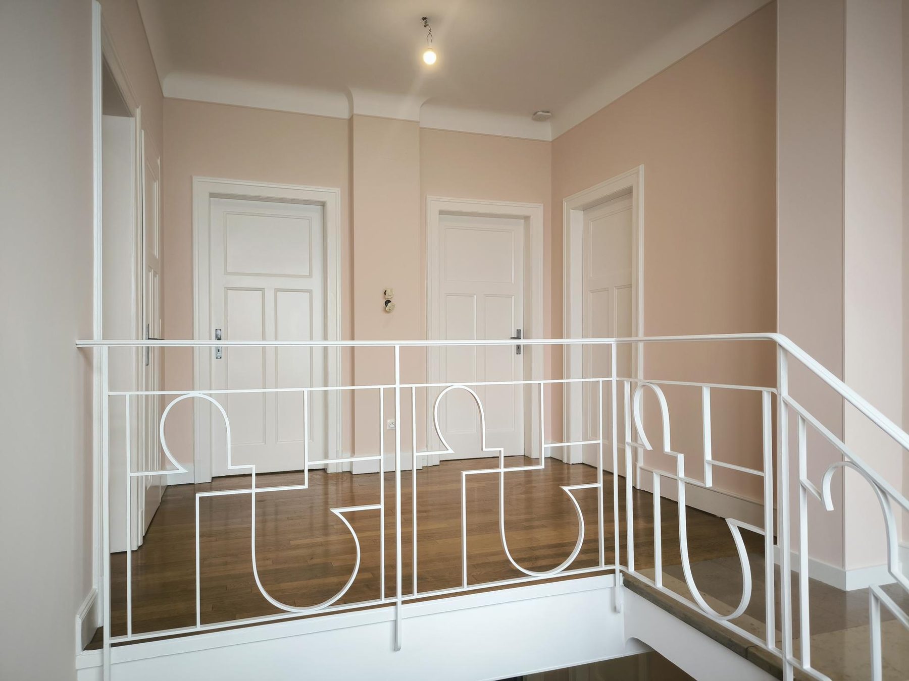 Palier aux murs rose poudré et garde-corps blanc art déco