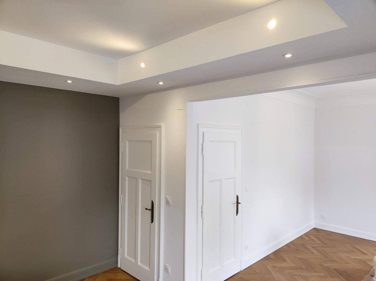 Pièce au mur taupe, portes blanches et parquet à bâtons rompus