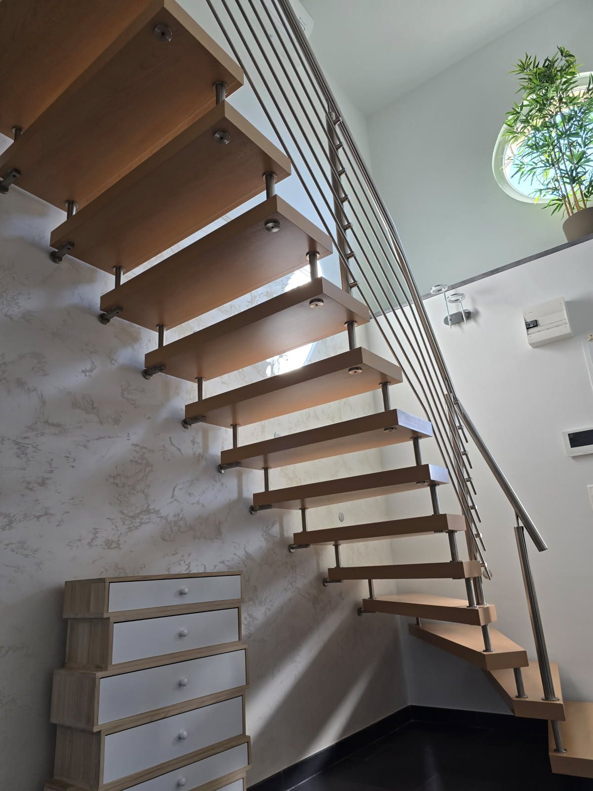 Mur en enduit décoratif sous un escalier suspendu en bois